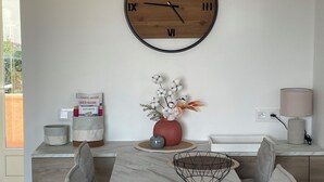 A modern dining area with a marble table, grey upholstered chairs, a wooden clock, and a vase with flowers. - 3* duplex apartment with balcony facing the sea (Sainte-Maxime)