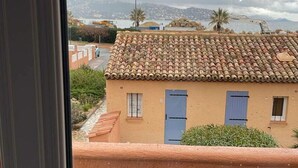 A balcony with a table and chairs, a view of a building with a tiled roof, and a mountainous landscape in the background. - 3* duplex apartment with balcony facing the sea (Sainte-Maxime)