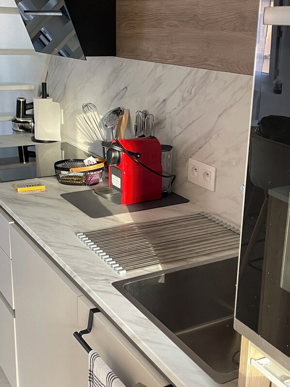 A kitchen with a marble countertop, a red appliance, and various utensils. - 3* duplex apartment with balcony facing the sea (Sainte-Maxime)