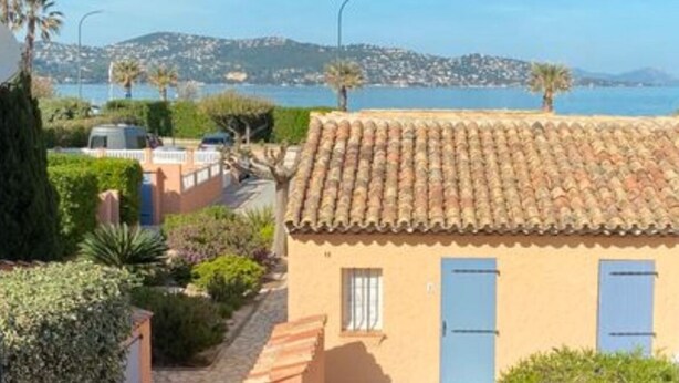 A balcony with a table and chairs, overlooking a coastal area with terracotta-roofed buildings and a clear blue sky. - 3* duplex apartment with balcony facing the sea (Sainte-Maxime)