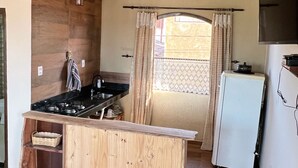 A compact kitchen with a wooden countertop, a gas stove, and a refrigerator.
