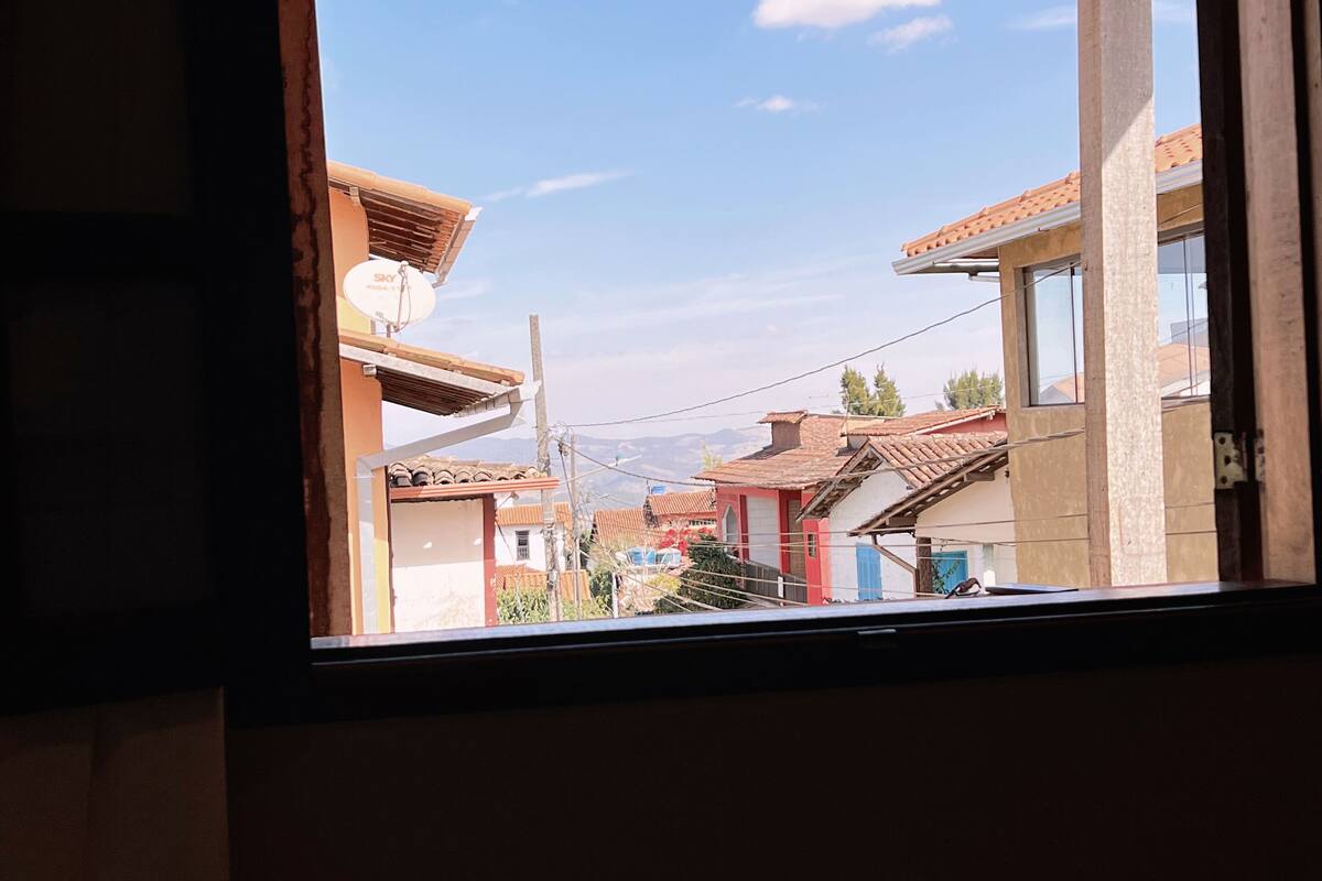 Une vue à travers la fenêtre d’un bâtiment doté d’un plafond en bois, d’une antenne parabolique et d’un ciel dégagé.