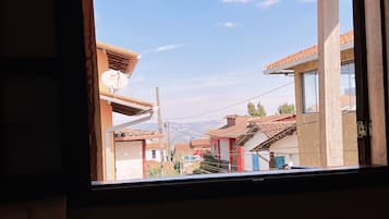 A view through a window of a building with a wooden ceiling, a satellite dish, and a clear sky.