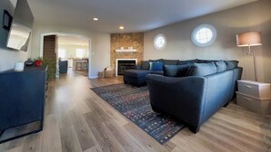 A modern living room with a dark grey sofa, a fireplace, and a stone accent wall.
