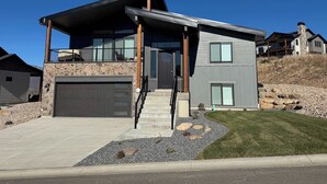 A modern two-story house with a stone facade, a garage, and a covered porch. - Eden House: Ski Retreat w/ Hot Tub & Views (Eden)