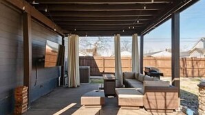 An outdoor patio area with a covered seating area, a barbecue grill, and a view of the backyard. - Lucky Bachelor 5 Min to Broadway (Nashville)
