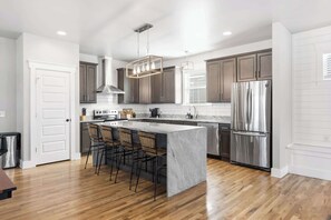 A modern kitchen with dark wooden cabinets, stainless steel appliances, and a central island with bar stools. - Lucky Bachelor 5 Min to Broadway (Nashville)