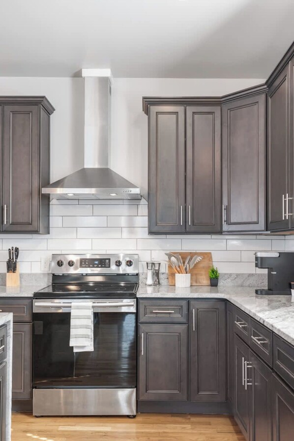A modern kitchen with dark cabinetry, a stainless steel range, and a white tiled backsplash. - Lucky Bachelor 5 Min to Broadway (Nashville)