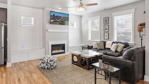 A modern living room with a fireplace, a sofa set, a coffee table, and a ceiling fan. - Lucky Bachelor 5 Min to Broadway (Nashville)