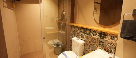 A bathroom with a glass-enclosed shower, a toilet, and a sink.