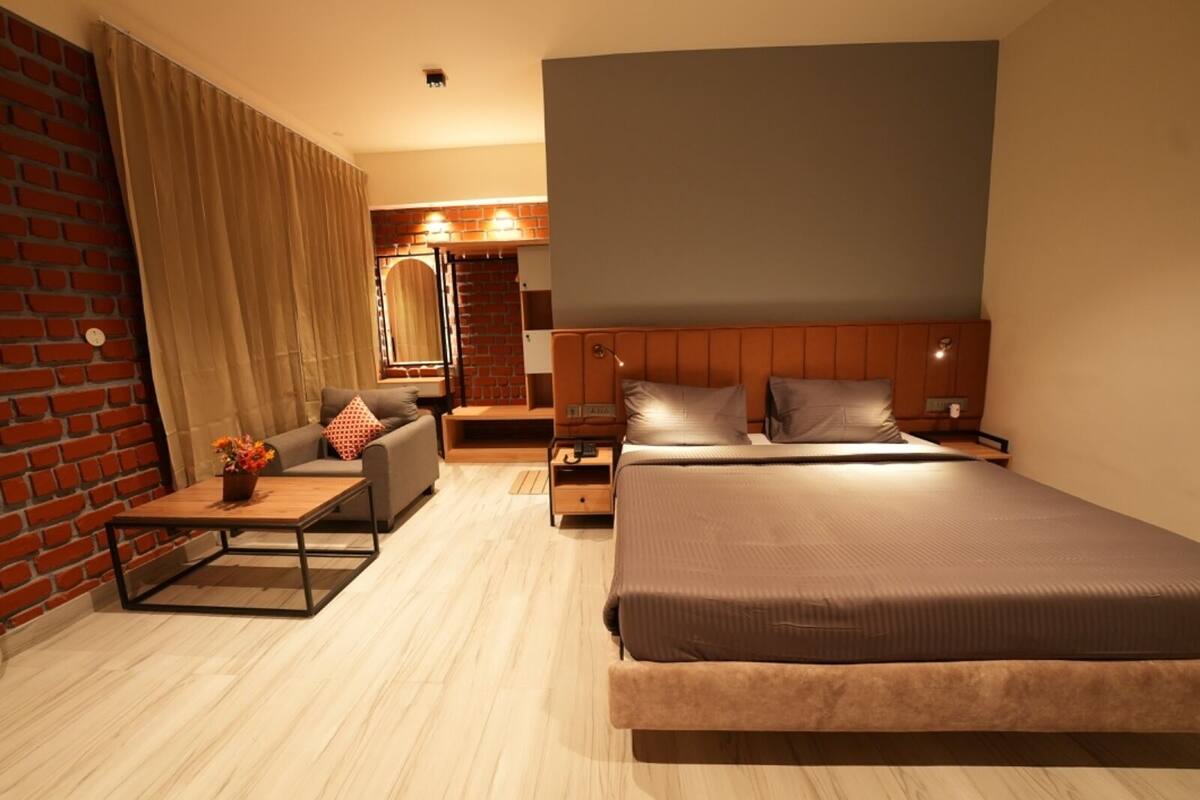 Ein modernes Hotelzimmer mit einem großen Bett, einer Couch, einem kleinen Tisch und einer Backsteinwand.