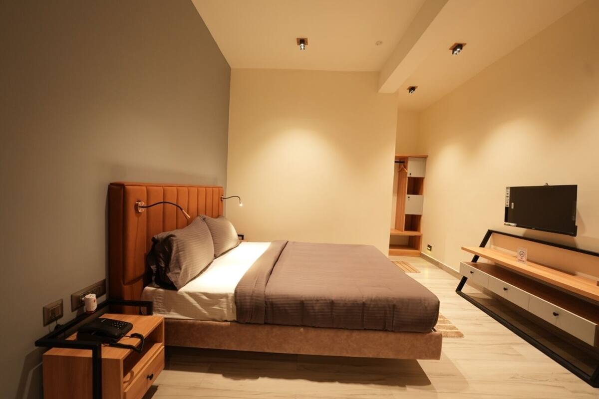 Ein modernes Schlafzimmer mit Bett, Nachttisch, Fernseher und integriertem Kleiderschrank.