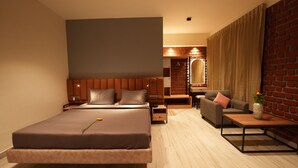 Une chambre d’hôtel moderne dotée d’un grand lit, d’un coin salon avec un canapé et un fauteuil, d’une petite table et d’un mur décoratif en briques.