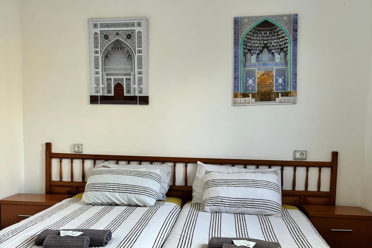 A double bed with striped bedding and two pillows, a wooden headboard, and two nightstands with lamps.