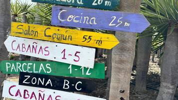 Um painel de madeira com vários indicadores de direção apontando para diversas atrações locais e distâncias.