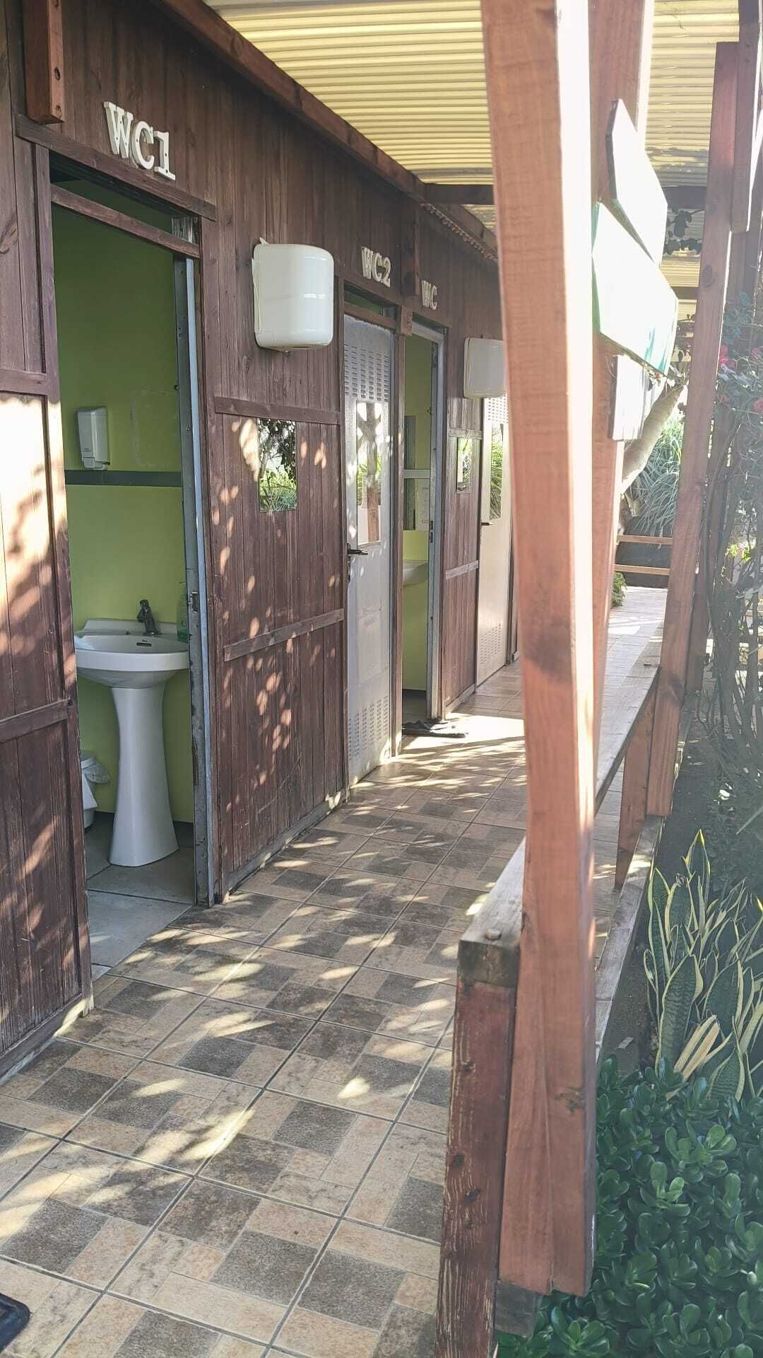 Un pasillo con puertas de madera identificadas como WC1 y WC2, que conduce a un baño con un lavamanos.