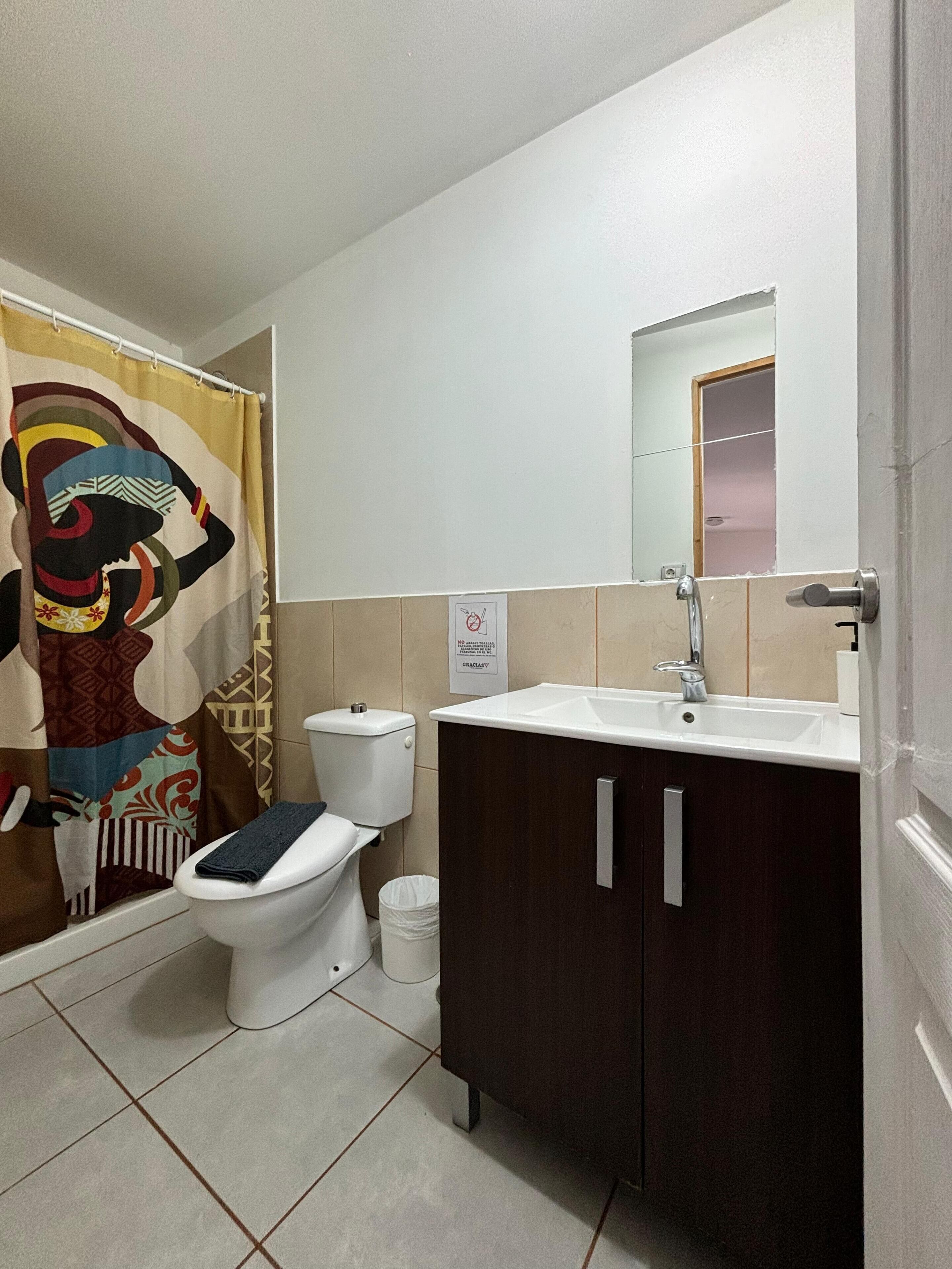 A bathroom with a toilet, sink, and shower curtain.