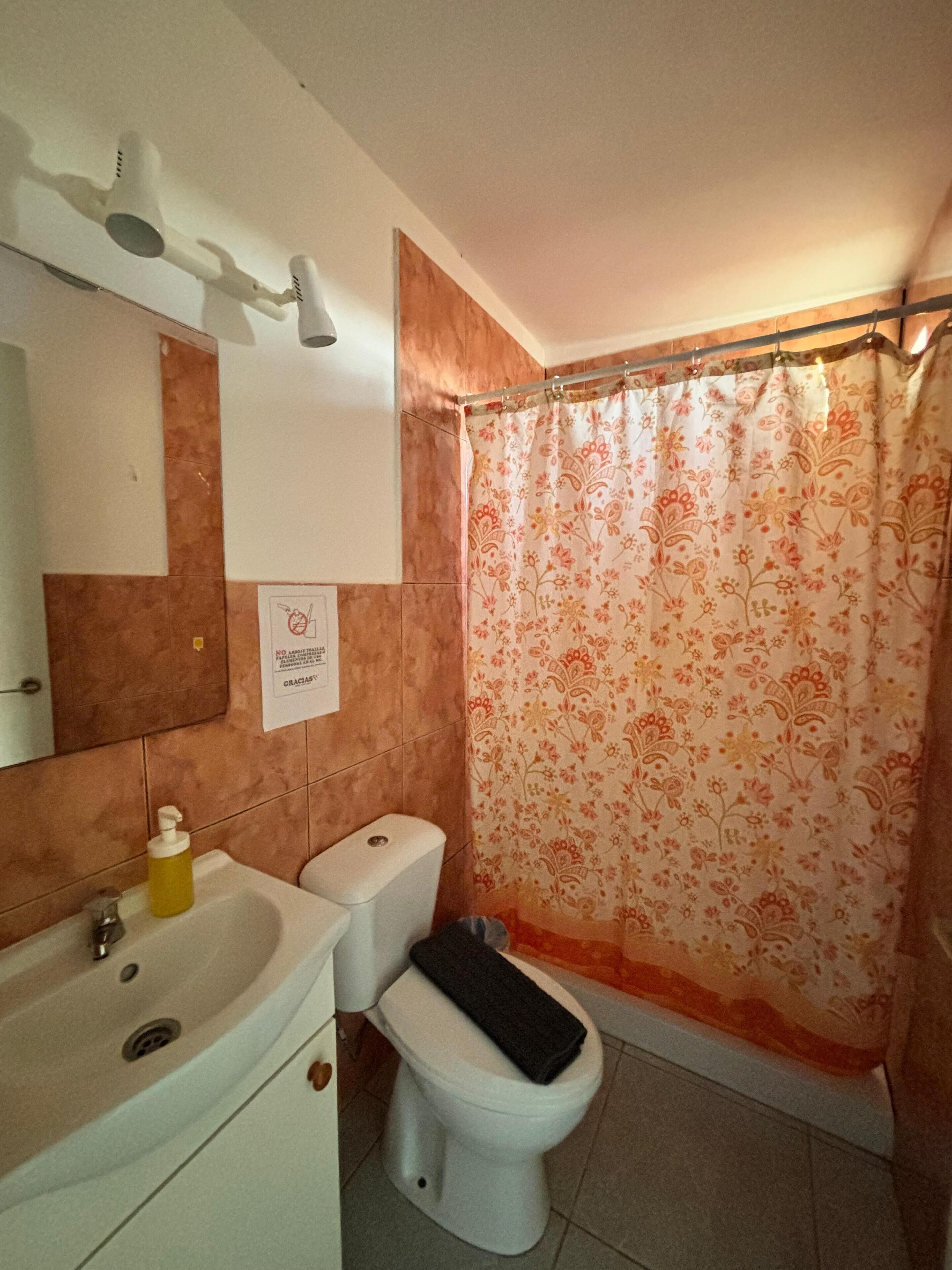 A bathroom with a sink, toilet, and shower curtain.