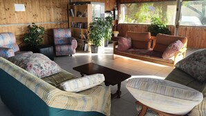 Un salon confortable avec un canapé, des fauteuils, une table basse et une bibliothèque.
