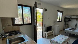 Une cuisine compacte équipée d’un évier, d’une cuisinière et d’un petit coin repas avec une table et un banc.