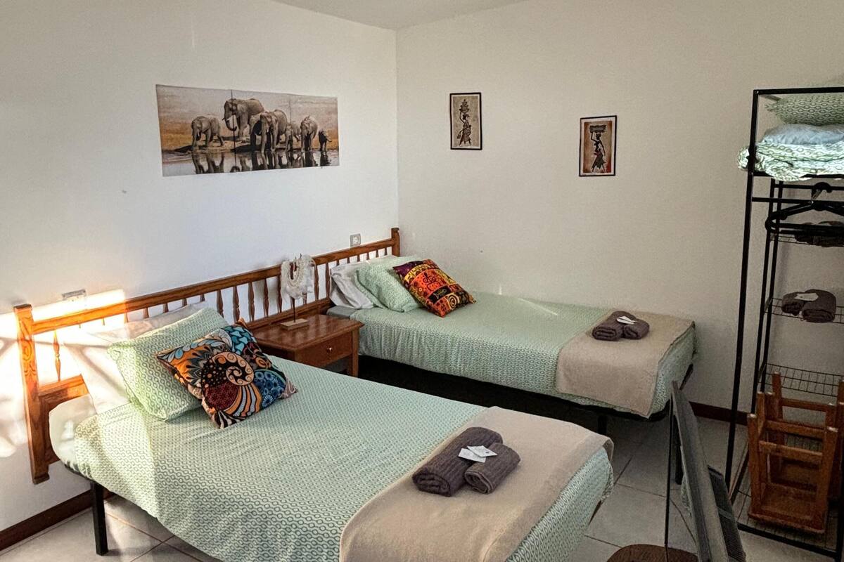 A room with two single beds, a wooden nightstand, a small table, and a bunk bed.