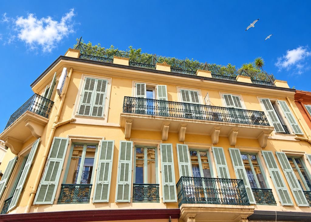 A multi-story building with balconies, green shutters, and a clear blue sky.