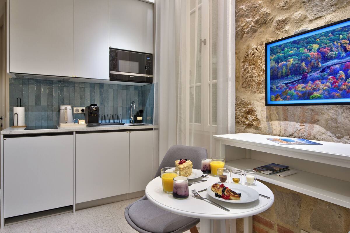 A modern kitchen with a dining area, a stone wall, and a large window.