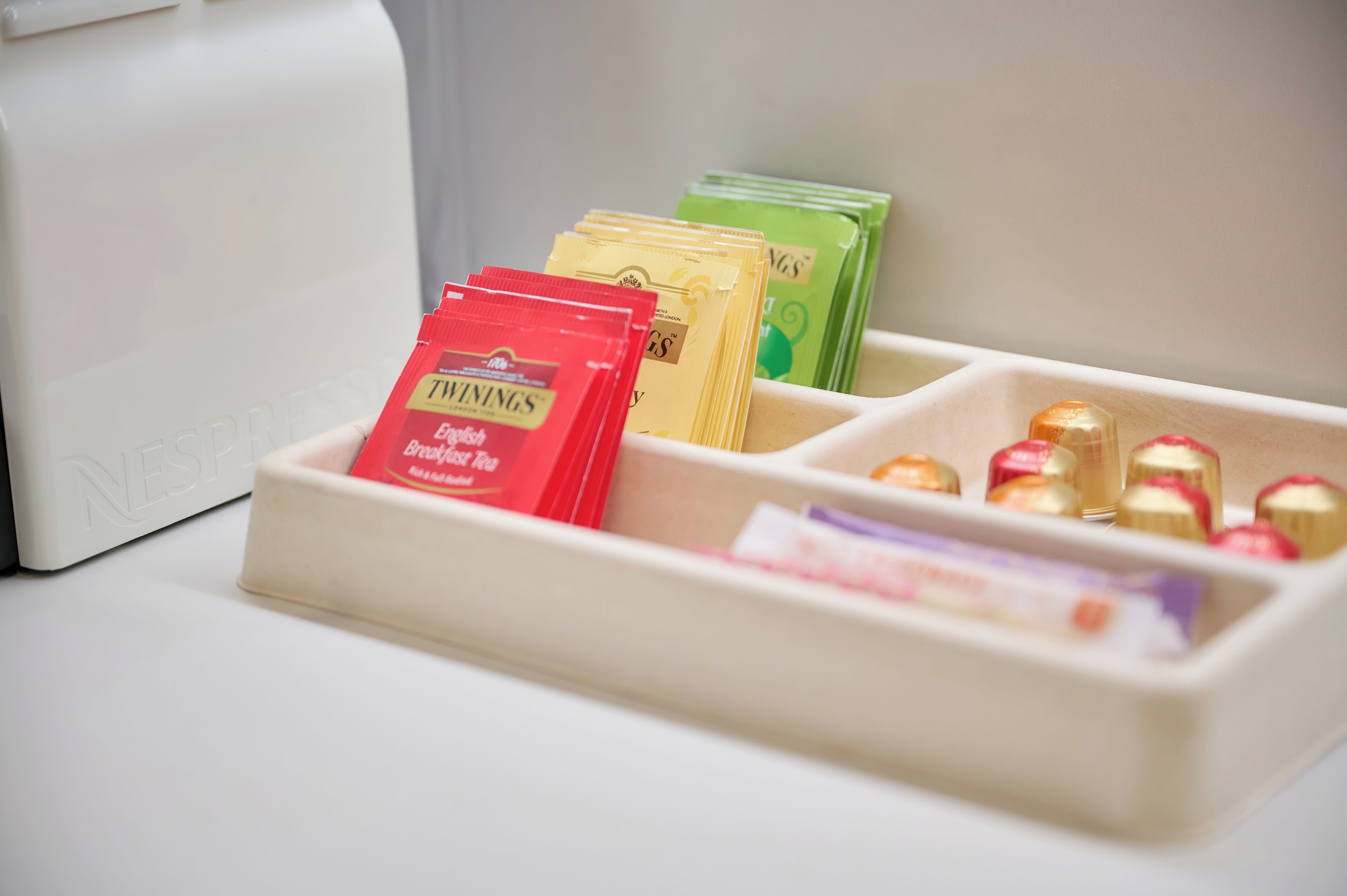 Un plateau avec des sachets de thé et des chocolats.