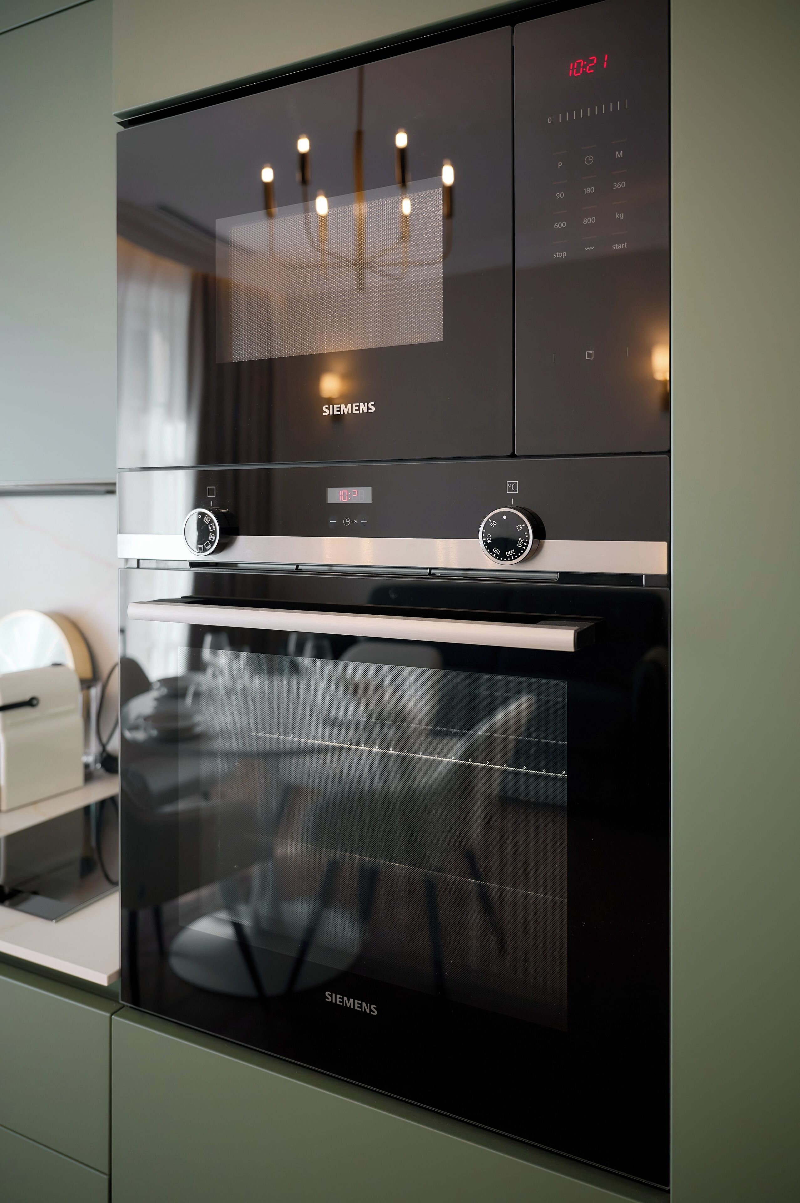 A modern kitchen with a built-in oven and microwave, featuring a digital clock and control panel.