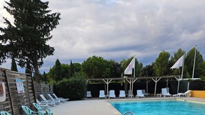 Una piscina con sillas de descanso y una zona cubierta.