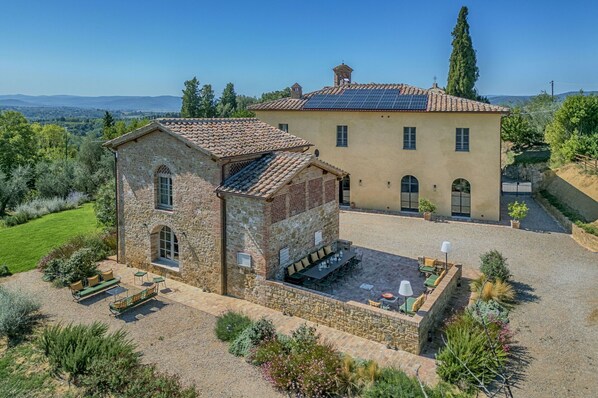 A two-story stone building with a courtyard, a dining area with outdoor seating, and a view of the surrounding landscape. - Villa in Siena with 6 bedrooms sleeps 11 (Siena)