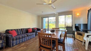 A living room with a sofa set, a dining table with chairs, a ceiling fan, and a TV.