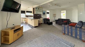 Un salon avec un téléviseur, un canapé et un petit coin cuisine.