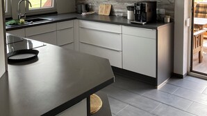Ett modernt kök med vita skåp, en inbyggd ugn och en stor köksö med en diskho.