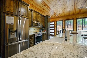 A modern kitchen with stainless steel appliances, wooden cabinets, and a large island with a sink.