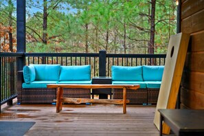 A wooden deck with a wicker sofa and a wooden table.