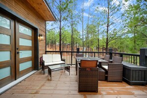 Terraza de madera con muebles de exterior y vistas a árboles.