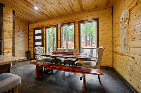 A wooden interior with a large dining table, chairs, and a bench.