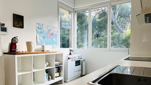 Una cocina moderna con armarios blancos, una estufa y un amplio ventanal con vistas a zonas verdes.
