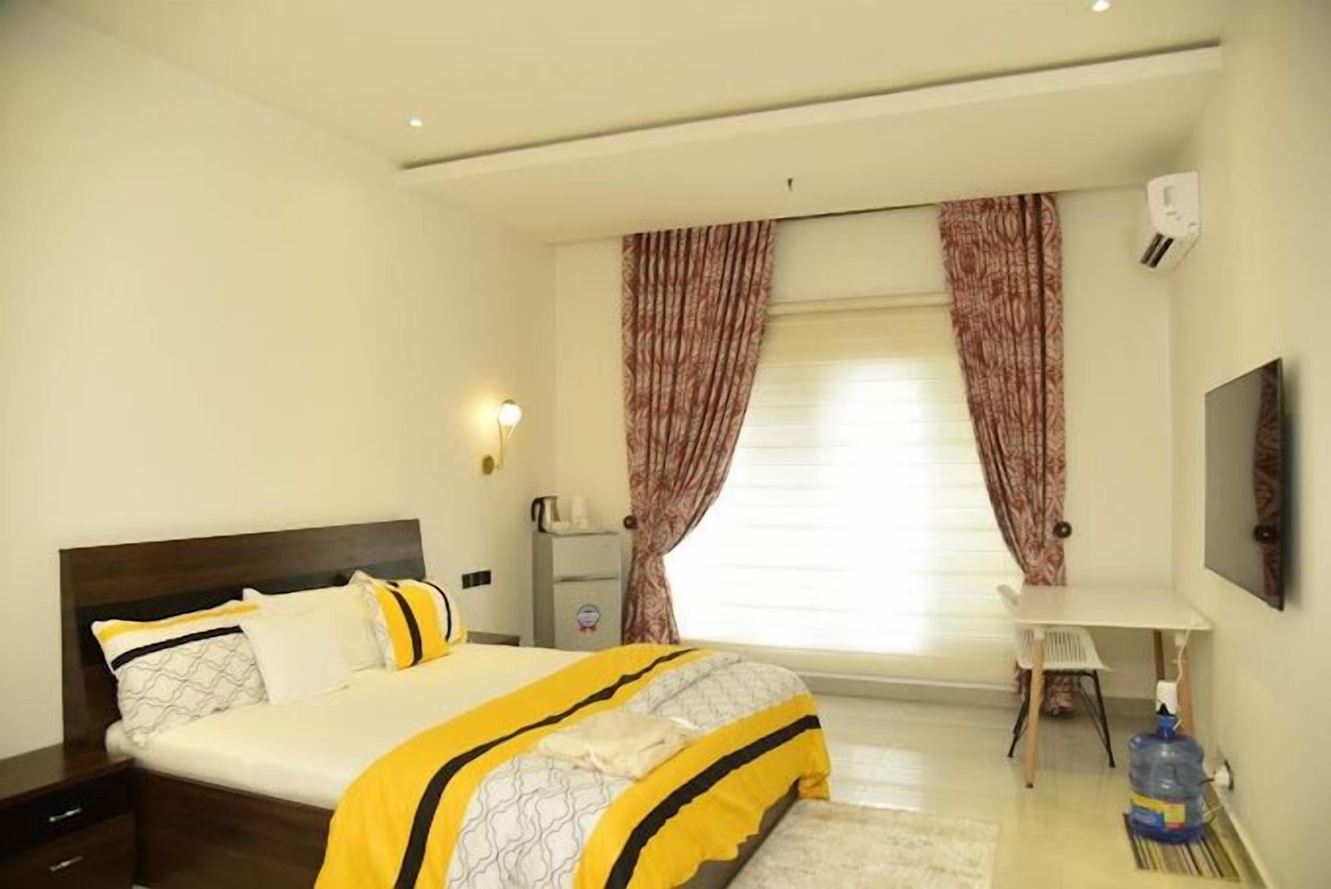 A bedroom with a bed, a desk, and a water dispenser.