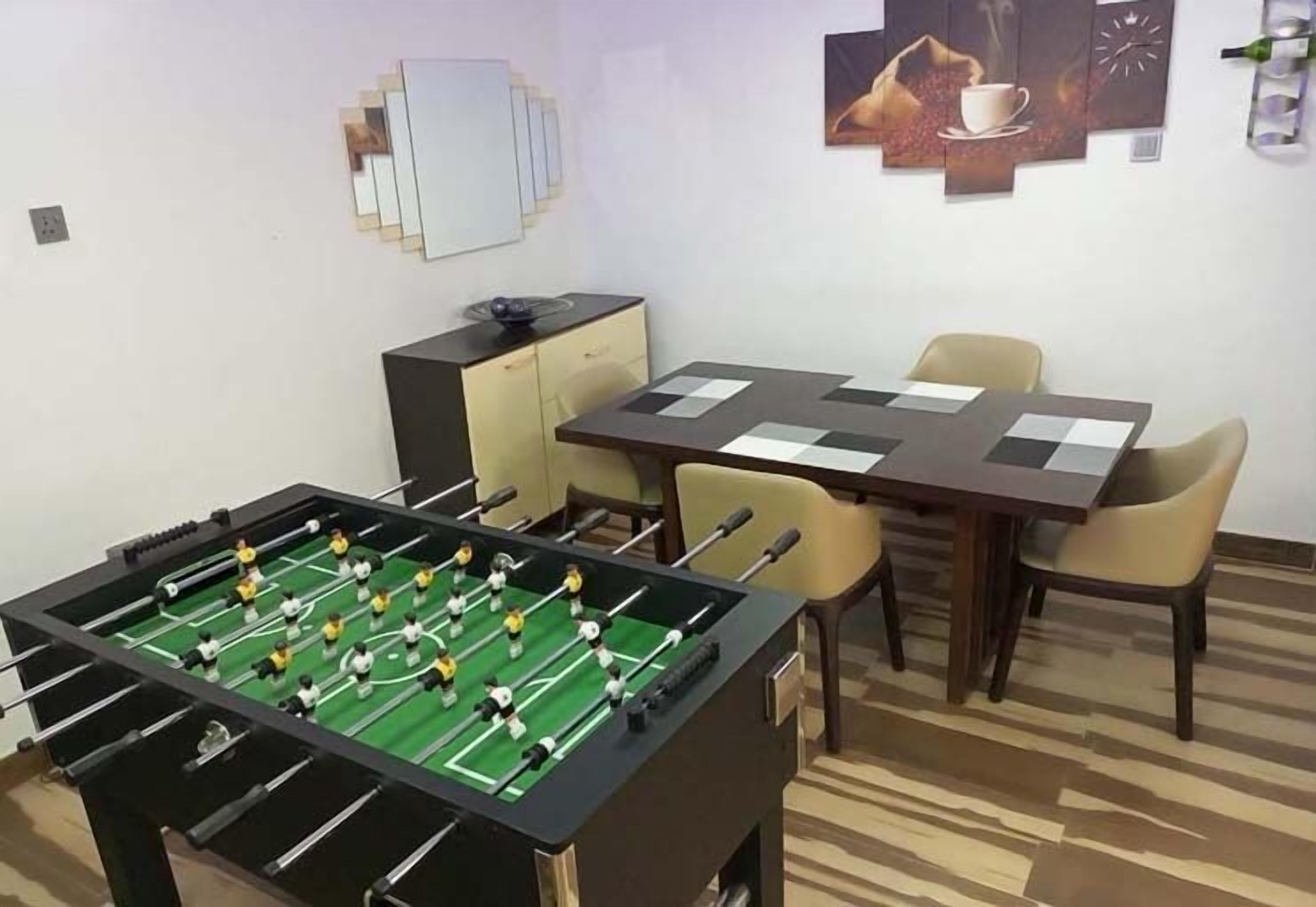 Une pièce comprenant une table de baby-foot, une table à manger avec des chaises et un petit meuble.