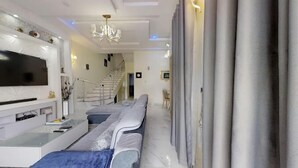 Una sala de estar moderna con un televisor de pantalla plana, un sofá y una escalera que sube a otro nivel.