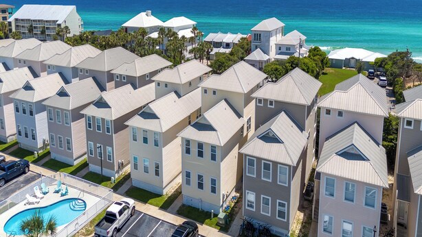 A coastal residential area with multiple two-story houses, a swimming pool, and a view of the ocean.