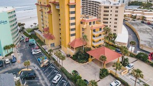 A multi-story hotel with a central courtyard, parking area, and a view of the beach. - ☀️Oceanfront-Pool+Hot Tub-3BR-Atlantic Villas 601☀️ (New Smyrna Beach)