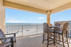 A balcony with a view of the beach, outdoor furniture, and a railing. - ☀️Oceanfront-Pool+Hot Tub-3BR-Atlantic Villas 601☀️ (New Smyrna Beach)