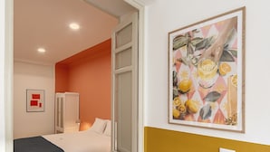 Ein Hotelzimmer mit einem Bett, einem Kleiderschrank, einer Tür zu einem anderen Raum und einem Bild an der Wand.