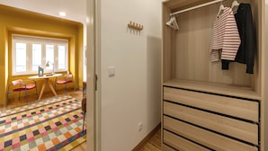 Ein Zimmer mit einem Holzschrank, einem farbenfrohen Teppich und einem Vorhangfenster.