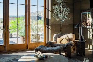 A room with a large glass door, a sofa, a small table, and a lamp.
