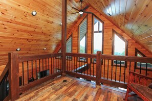A wooden interior with a sloped ceiling, a staircase, and multiple windows. - A Bear's Cave: Cozy 3BR Cabin with Hot Tub & Mountain Views! (Bryson City)