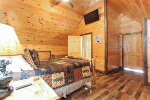 A cozy cabin bedroom with a bed, a desk, and a television. - A Bear's Cave: Cozy 3BR Cabin with Hot Tub & Mountain Views! (Bryson City)